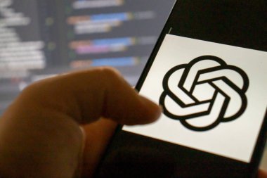Varşova, Polonya - 1 Ekim 2023: Bir kullanıcı ChatGPT logosunu bulanık bir kodlama geçmişi, ışıklandırma teknolojisi ve iletişimi gösteren akıllı bir telefonla etkileşime girer.