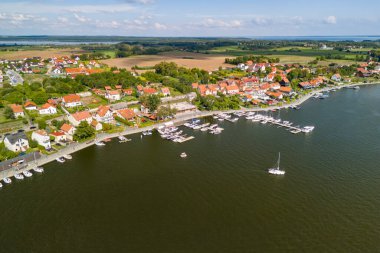 Mikoajki 'nin yazın göl kenarında sakin suları ve bereketli manzarayı aydınlatan bir tekne ile hava manzarası..