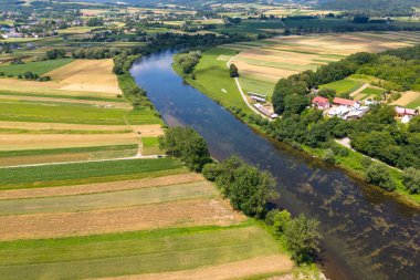 Yaz boyunca Polonya 'daki bir nehrin insansız hava aracı görüntüsü onun dolambaçlı yolunu ve canlı yeşil çevresini hava perspektifinden vurguluyor..