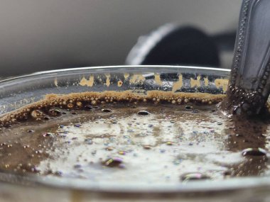 Köpüklü bir kahve fincanının yakın çekimi parıldayan kabarcıklar ve zengin dokular yemek ve içecek fotoğrafçılığı için mükemmel.