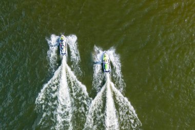 Güneşli bir günde iki jet ski, su sporlarının ve yaz eğlencesinin heyecanını vurgulayan sıçramalar ve dalgalar yaratmak için yarışıyor..
