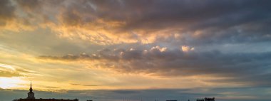 Gökyüzündeki bulutları boyayan canlı renklerle ufuk çizgisinin üzerinde güzel bir günbatımının görüntüsü. Doğanın sanatını gösteren sakin bir an..