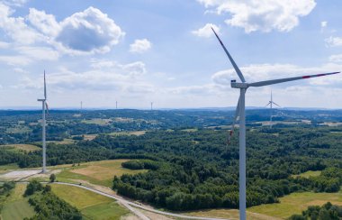 Breathtaking aerial view of wind turbines in a lush green landscape showcasing renewable energy in harmony with nature. A perfect representation of sustainability and technological advancement.