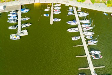 Etrafı yeşilliklerle çevrili sakin bir marinaya yanaşmış güzel teknelerin hava manzarası tatil ve su aktiviteleri için mükemmel..