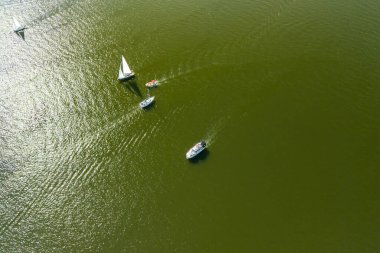 Güneş ışığı altında sakin yeşil bir göl üzerinde yüzen birkaç teknenin havadan görüntüsü. Denize açılmak için mükemmel bir gün. Doğanın güzelliğini ve açık hava aktivitelerini göstermek için..