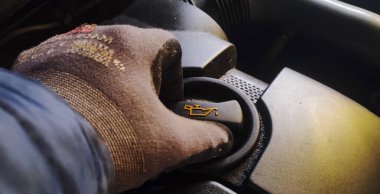 Rzeszow Polonya - 20 Eylül 2024: Bakım ve araç bakımını vurgulayan bir otomobil motorunun yağ seviyesini kontrol eden çalışma eldivenli bir elin yakın çekimi.