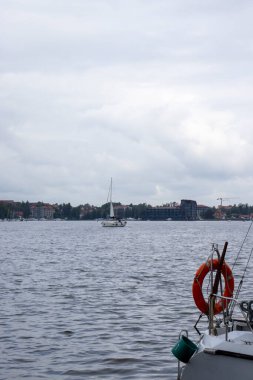 Mikolajki Polonya - 20 Eylül 2024: Mikolajki 'nin göl kenarındaki teknelerinin ve arka plandaki manzaralı binaların huzurlu manzarası. Seyahat ve yaşam tarzı temaları için ideal.