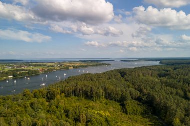 Mikolajskie Gölü 'nün havadan görünüşü yemyeşil ve güneşli bir günde yelkenli tekneleriyle çevrili.