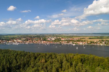 Mikolajki 'nin güzel bir hava manzarası yemyeşil ormanları sergiliyor dingin gölü ve dağınık bulutlu mavi gökyüzünün altında büyüleyici bir kasabayı..