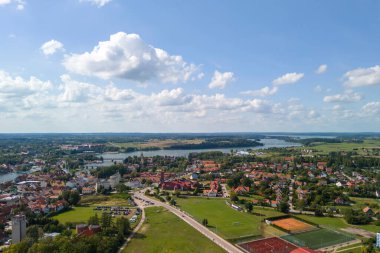 Mikolajki 'nin açık mavi gökyüzü altında güzel manzaralar, göller ve renkli binalar gösteren hava manzarası