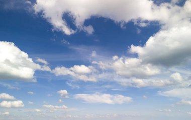 Pofuduk beyaz bulutlarla dolu güzel bir gökyüzü dingin bir günün özünü yakalamak için mükemmel bir mavi arkaplan karşısında..