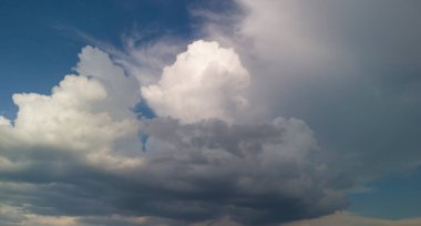 Mavi gökyüzüne karşı dramatik bulut oluşumları güzel ve sakin bir atmosfer yaratıyor. Doğa temalı projeler veya arkaplan kullanımı için mükemmel.