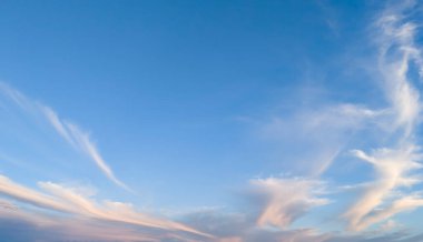 Gün batımında yumuşak bulutlarla dolu güzel bir gökyüzü sakin ve sakin bir atmosfer yaratıyor. Arka plan, doğa temalı projeler veya atmosferik tasarımlar için mükemmel..