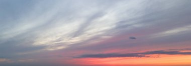 Sakin bir günbatımı gökyüzü, turuncu pembe ve mor güzel renkler yumuşak bulutlara karışıyor ve sakin bir atmosfer yaratıyor..