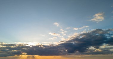 Bulutlar ve canlı renklerle çarpıcı bir günbatımı gökyüzü rahatlamayı davet eden sakin bir atmosfer yaratıyor..