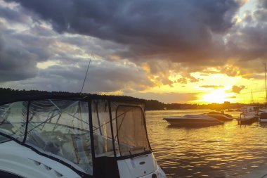 Sakin suların üzerinde güzel bir günbatımı. Silüet içinde tekneler huzurlu ve resim gibi bir manzara yaratıyor..