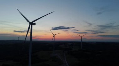 Gün batımında rüzgâr türbinleri çiftliğinin manzarası. Rüzgar türbini alternatif enerji üretiyor