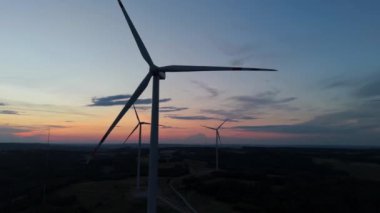 Gün batımında rüzgâr türbinleri çiftliğinin manzarası. Rüzgar türbini alternatif enerji üretiyor