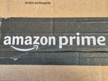 Rzeszow, Polonya - 15 Ekim 2024: Çevrimiçi alışveriş ve dağıtım hizmetlerinin popülaritesini gösteren mukavva bir paketin üzerindeki Amazon Prime logosunun yakın çekimi.