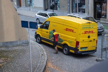 Rzeszow Polonya - Ekim 12023: DHL dağıtım aracı paketleri dağıtırken dar bir sokağa park etti. Kentsel lojistik ve ulaşım faaliyette.