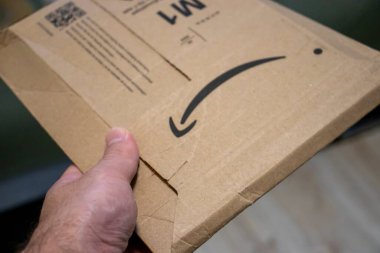 Varşova Polonya - 20 Eylül 2024: İçinde Amazon logosu olan bir karton paketi tutan bir el. Yakın çekim çevrimiçi alışveriş paketleme ve teslim yönünü vurguluyor.