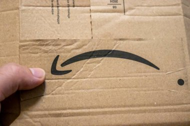 Varşova Polonya - 20 Eylül 2024: E-ticaret şirketinin ambalaj ve tanınabilir logosunu vurgulayan Amazon markalı bir karton kutuyu tutan elin yakın çekimi.