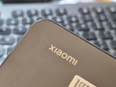Varşova, Polonya - 20 Eylül 2024: Modern tasarım ve logosunu gösteren bir Xiaomi akıllı telefonunun yakın çekimi bulanık bir klavye arka planına yerleştirildi. Teknoloji makaleleri için ideal.