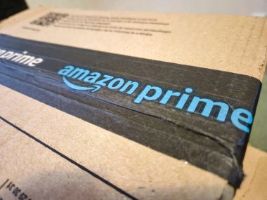 Rzeszow, Polonya - 20 Eylül 2024: Çevrimiçi alışverişin kolaylığını vurgulayan Amazon Prime marka ve dokusunu gösteren bir paketin yakın çekimi.