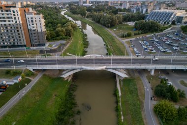 Rzeszow, Polonya - 20 Haziran 2024: Rzeszow 'daki bir nehir üzerindeki modern bir köprünün havadan görünüşü, yeşil parklar ve çevresindeki kentsel gelişmeler.