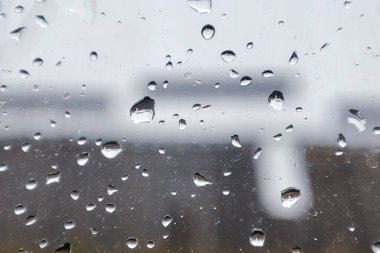 Camdaki yağmur damlaları güzel bir bokeh etkisi yaratır, bulanık arka planlar ve sakin bir ortam yaratır.