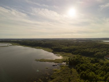 Parlak güneşin altındaki yemyeşil yemyeşil bir gölün havadan görünüşü.