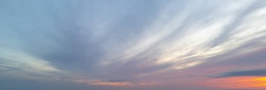 Huzurlu bir günbatımı gökyüzü, mavi, pembe ve turuncu tonlarda canlı bulutlar, rahatlama ve güzelliği çağrıştıran sakin bir atmosfer yaratıyor..