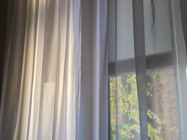 Yumuşak güneş ışığı perdelerin arasından süzülüyor. İçerde sıcak ve davetkar bir atmosfer yaratıyor.