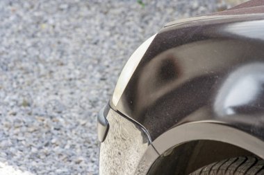 Bir arabanın arka köşesine yakın çekim yaparak yansıtıcı yüzeyini çakıllı arka planıyla gösterir. Otomotiv temaları ya da araba bakım konuları için mükemmel.