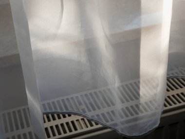 Saf beyaz perde radyatörün üzerine hafifçe örtülmüş güneş ışığının rahat bir odada huzurlu ve sakinleştirici bir atmosfer yaratmasına olanak sağlıyor..