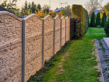 Dekoratif taştan çitlerle kaplı, yeşil çimenler ve çimlerle süslenmiş, bakımlı bir bahçe yolunun manzarası..