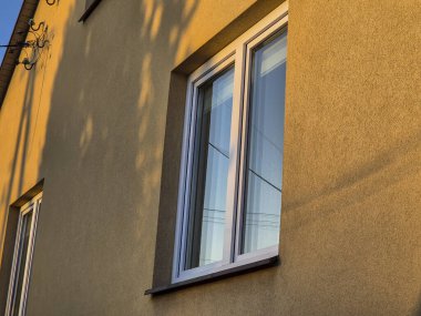 Modern pencerelerin sıcak akşam ışığında yıkandığı bir apartman duvarının yakın çekimi. Mimari ve ev tasarımı estetiği için ideal..