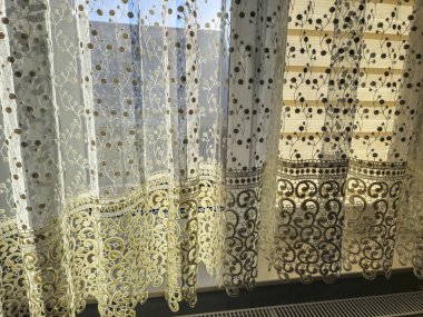 Güneş ışığıyla aydınlatılan güzel dantel perdeler bir evde rahatlatıcı bir atmosfer yaratıyor. İç dekorasyon ya da pencere işleme fikirleri için mükemmel.