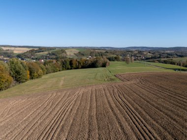 Bereketli yeşil tarlaların ve açık mavi gökyüzünün altındaki uzak tepelerin havadan görünüşü. Doğa temalı projeler için mükemmel.