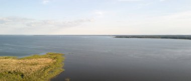 Berrak bir gökyüzü altında yemyeşil sularla çevrili engin bir su kütlesinin huzurlu görüntüsü doğanın sükunetini ve açık havanın güzelliğini yakalıyor..