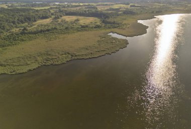 Bereketli yeşilliklerle çevrili sakin bir gölün havadan görünüşü doğanın sükunetini ve sudaki yansımalarını yakalıyor.