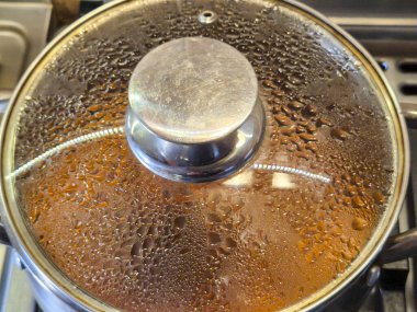 Bir tencere kapağının dış yüzeyinde buharlaşma var. Bu da pişirmeyi ya da kaynamayı gösteriyor. Yemek hazırlama temaları için mükemmel.