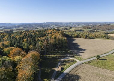 Sonbahar yapraklarının yuvarlanan tepeleri ve açık arazileri, berrak mavi gökyüzünün altında gösteren hava manzarası.