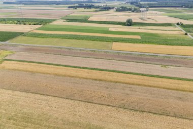 Kırsal bölgelerdeki çeşitli tarımsal uygulamaları gösteren renkli yama alanlarının havadan görünüşü. Canlı yeşiller sarı ve kahverengiler çarpıcı bir manzara yaratır..