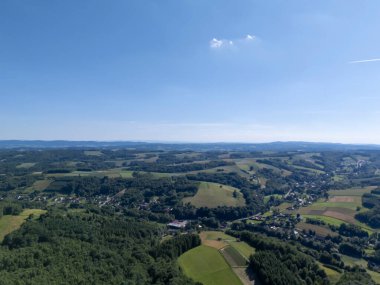 Bereketli yeşil tarlaların ve açık mavi gökyüzünün altındaki yuvarlanan tepelerin havadan görünüşü