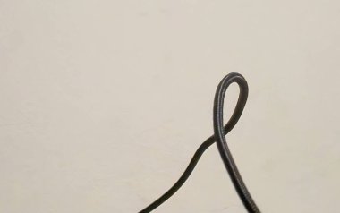 Siyah bir kabloyu düz bir arkaplana yakın plan çekerek tasarımın dokusunu ve basitliğini gösteriyor. Minimalist temalar için mükemmel.