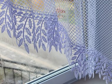 Güzel dantel perdeler pencerenin üzerine nazikçe örtülmüş narin bir doku ve yumuşak bir ışık yaratıyor. Ev dekorasyonu ve iç tasarım ilhamı için mükemmel..