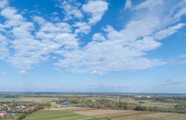 Parlak mavi gökyüzünün altında bulutlu yemyeşil tarlaların havadan görünüşü. Doğa geçmişi ve açık hava sahneleri için mükemmel..