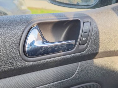 Arabanın iç kapı kolunun krom detaylandırma ve kontrol düğmelerini vurgulayan yakın çekimi. Otomotiv tasarımı ve iç özellikler için ideal.