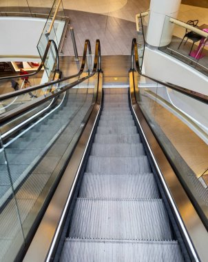 Bir alışveriş merkezinde modern bir yürüyen merdiven şık tasarımlar ve temiz çizgiler sergiliyor. Çağdaş mimari ve kentsel yaşam tarzını göstermek için mükemmel..